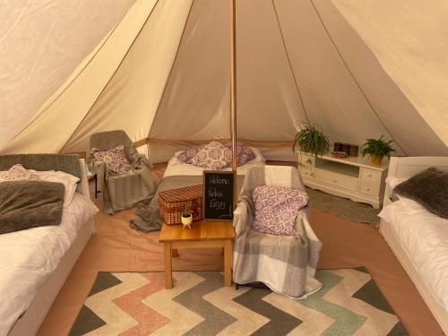 a tent with two beds and a table in a room at Trevena Cross Glamping in Helston