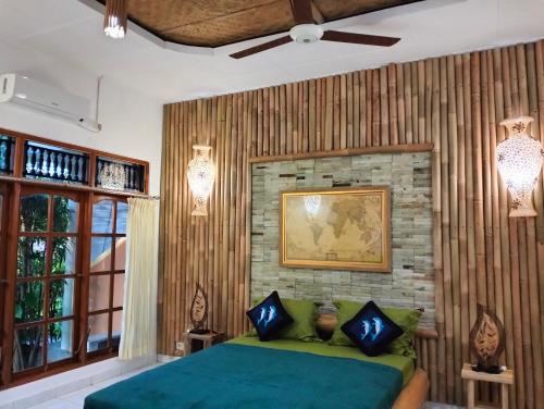 Kaia Lovina Guest House Junior Suite في لوفينا: غرفة نوم بسرير اخضر وجدار من الطوب
