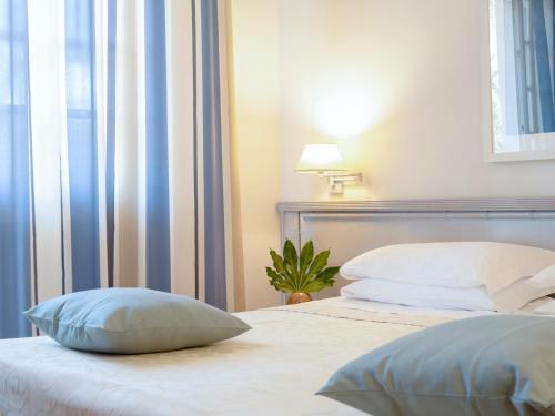 a bedroom with two beds with pillows and a plant at Hotel Mignon in Forte dei Marmi