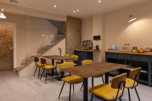 eine Küche und ein Esszimmer mit Holztischen und gelben Stühlen in der Unterkunft Room & Breakfast Civico 07 in Fontanellato