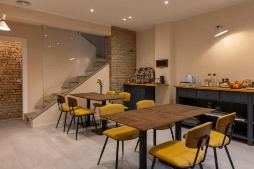 a kitchen and dining room with wooden tables and yellow chairs at Room & Breakfast Civico 07 in Fontanellato