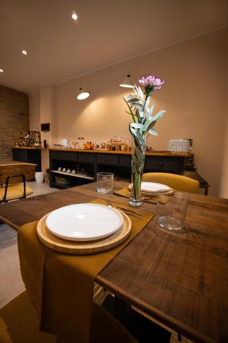 a table with a plate and a vase of flowers on it at Room & Breakfast Civico 07 in Fontanellato