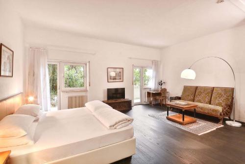 Villa Tivoli في ميرانو: غرفة نوم بيضاء مع سرير وأريكة