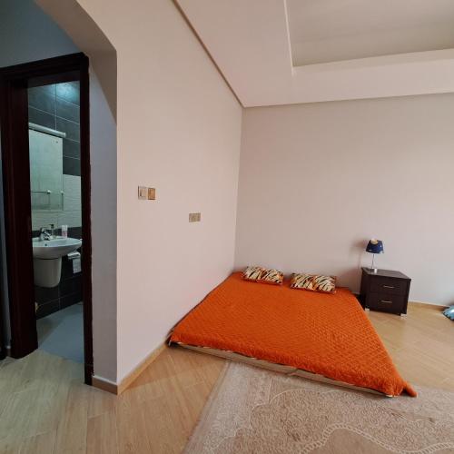 1 dormitorio con 1 cama con manta naranja en Modest Master Bedrom in a Duplex, en Mascate