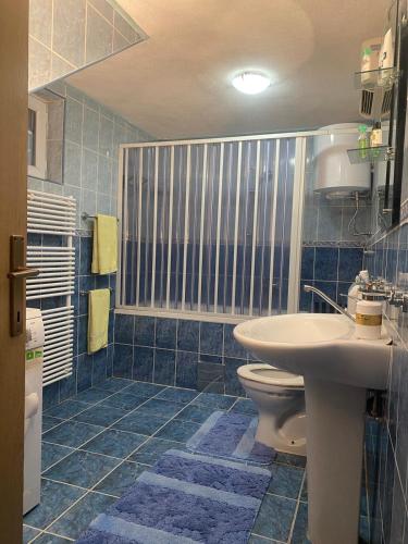 a blue tiled bathroom with a sink and a toilet at Forest House between Sarajevo & Vlasic in Busovača