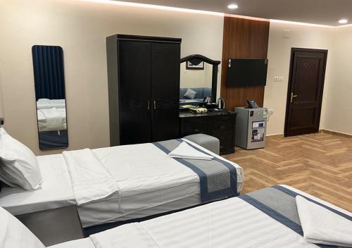 a hotel room with two beds and a mirror at Al Baida Suites Al Salam Branch in Al Madinah