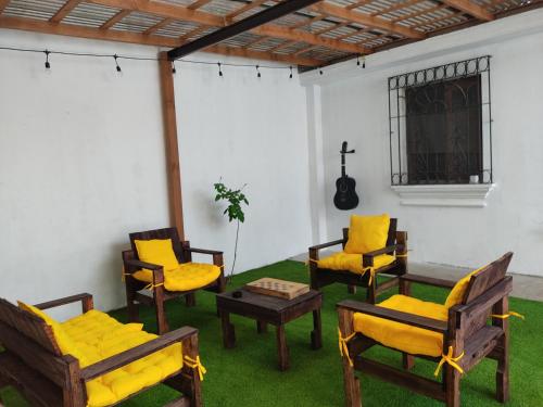 a room with chairs and a table and a guitar at Blue Moon Hostel in Antigua Guatemala