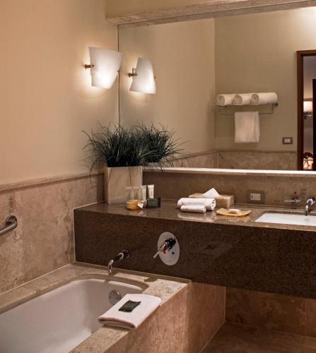 a bathroom with a tub and a large mirror at Grand Fiesta Americana Queretaro in Querétaro