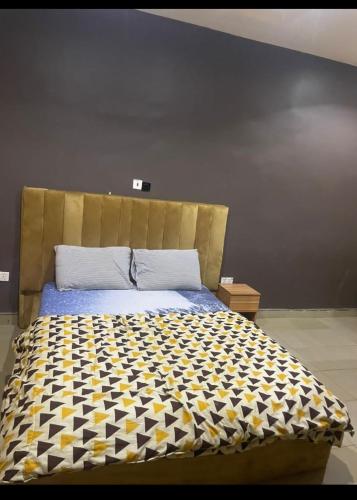 a bedroom with a bed with a black and yellow comforter at Thilda Hotel and Suites in Alimosho