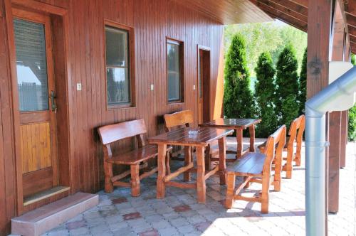 una mesa de madera y sillas en un porche en Néró Apartman en Veľký Meder