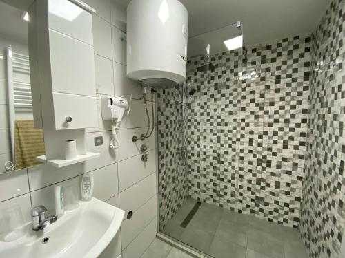 a bathroom with a sink and a shower with a mirror at FIA House in Skopje