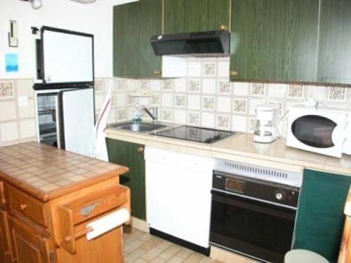 La cuisine est équipée d'armoires vertes et d'un four micro-ondes blanc. dans l'établissement Résidence Les Arenes - 4 Pièces 6 couchages PORT LEUCATE MAE-4534, à Port-Leucate