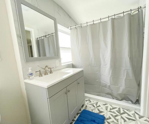 a white bathroom with a sink and a mirror at Beautiful room in prime location in Pinellas Park