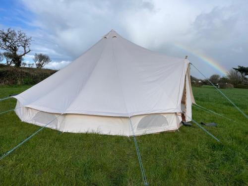 ein weißes Zelt auf einem Feld mit Regenbogen im Hintergrund in der Unterkunft Trevena Cross Bell Tent in Helston