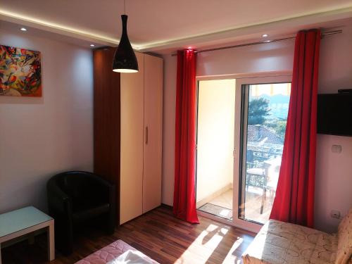 a living room with red curtains and a sliding glass door at Apartments Nancy in Kotor