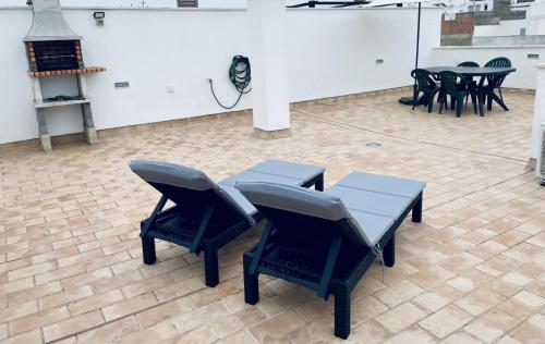 Ático Conil Playa con piscina, garaje, 2 terrazas-BBQ, Aire Ac y WIFI -SOLO FAMILIAS Y PAREJAS- في كونيل دي لا فرونتيرا: مجموعة من الكراسي والطاولات في الغرفة