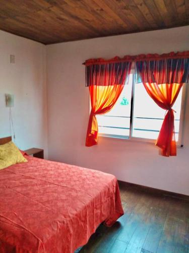 a bedroom with a red bed and a window at La Enramada in Victoria