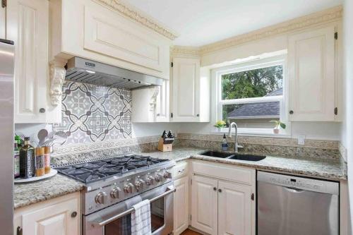 a white kitchen with a stove and a window at Spacious Retreat with guest house, game room, parking in N Tacoma in Tacoma