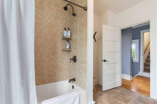 a bathroom with a bath tub and a shower curtain at Spacious Retreat with guest house, game room, parking in N Tacoma in Tacoma