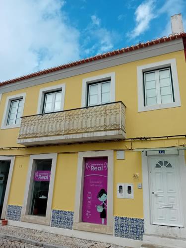 a yellow building with a purple sign in the window at Casa do Coronel in Alcochete