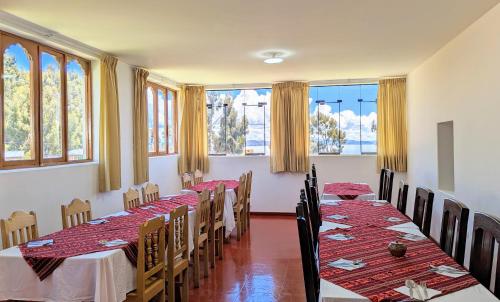 una fila de mesas en una habitación con ventanas en Amantani sol Andino en Ocosuyo