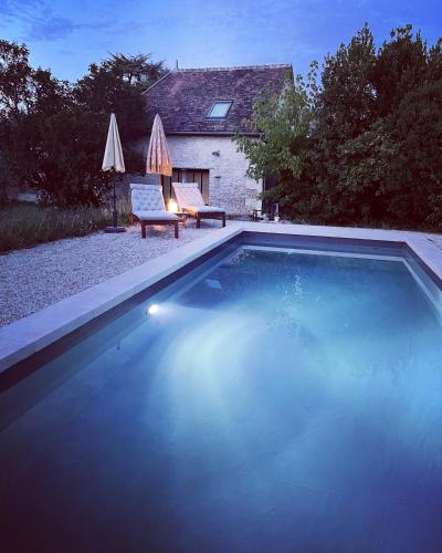 a swimming pool in front of a house with a chair and umbrella at Maison Saint Georges in Saint-Georges-sur-Cher