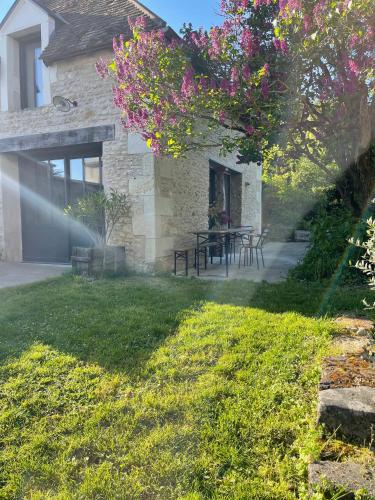 a house with a yard with a table and flowers at Maison Saint Georges in Saint-Georges-sur-Cher