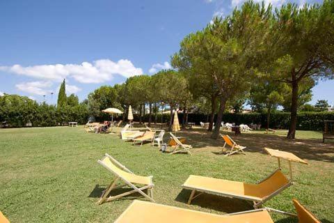 a group of lawn chairs and umbrellas in a field at Casa vacanze Ricky in Porto Recanati