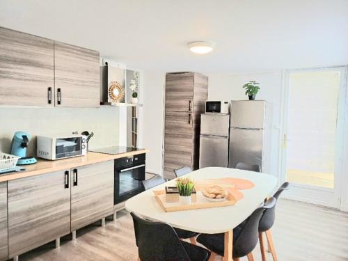 eine Küche mit einem weißen Tisch und eine Küche mit einem Kühlschrank in der Unterkunft La Belle Du Thil - Spacieuse - Proche Aéroport in Beauvais