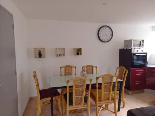 une table à manger avec des chaises et une horloge murale dans l'établissement Appartement Chez Marcel, à Saint-Lager-Bressac