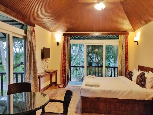 ein Schlafzimmer mit einem Bett und einem großen Fenster in der Unterkunft Ocean Pearl Beach Resort, Havelock in Havelock Island