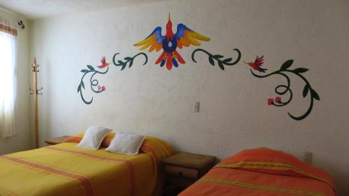a room with two beds and a wall with a painting on it at Posada del Fraile in Tepotzotlán