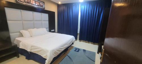 a bedroom with a bed and a blue curtain at مهاد للشقق المخدومه in Najran