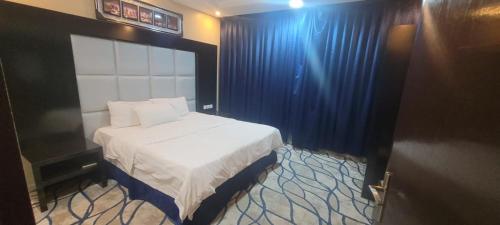 a bedroom with a bed with a blue curtain at مهاد للشقق المخدومه in Najran