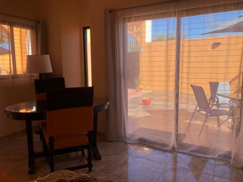 Cette chambre dispose d'une porte coulissante en verre avec une table et des chaises. dans l'établissement Tres Iguanas Apart Hotel - New, cozy & spacious flats, short walk to beach, à Loreto