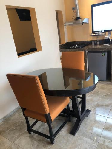 a glass table with orange chairs and a kitchen at Tres Iguanas Apart Hotel - New, cozy & spacious flats, short walk to beach in Loreto