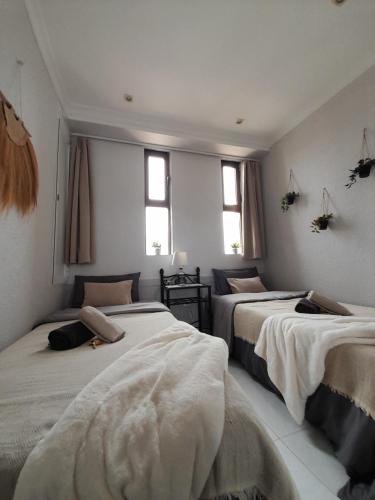 een slaapkamer met 2 bedden en 2 ramen bij Luxury private apartment at the beach in a 4 star hotel first beach line in Fuengirola