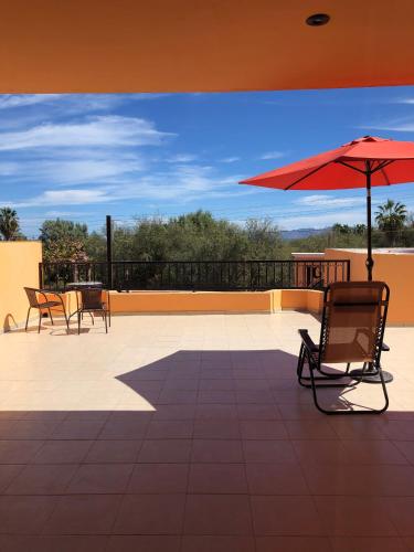 a patio with two chairs and a red umbrella at Tres Iguanas Apart Hotel - New, cozy & spacious flats, short walk to beach in Loreto