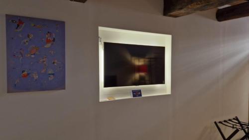 una TV a schermo piatto su una parete con un dipinto di Affittacamere Leoncorno Ferrara a Ferrara