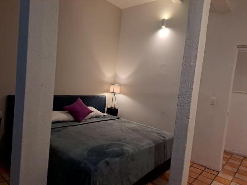 a bedroom with a bed with a purple pillow at Hotel Tao in Atlixco