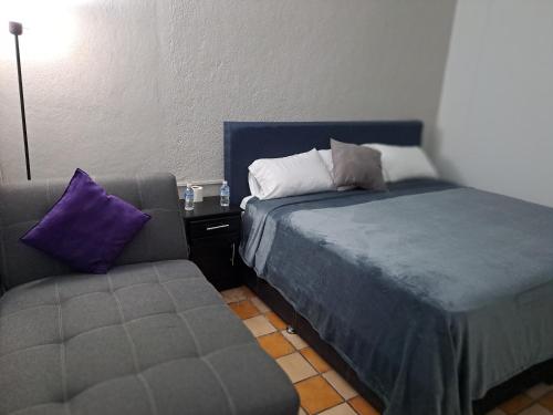 a bedroom with a bed and a couch and a chair at Hotel Tao in Atlixco