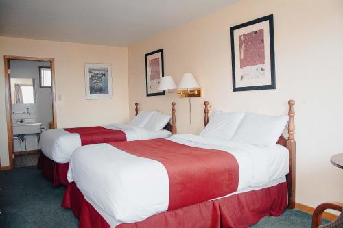 a hotel room with two beds with red and white sheets at Ceilidh Country Lodge in Baddeck
