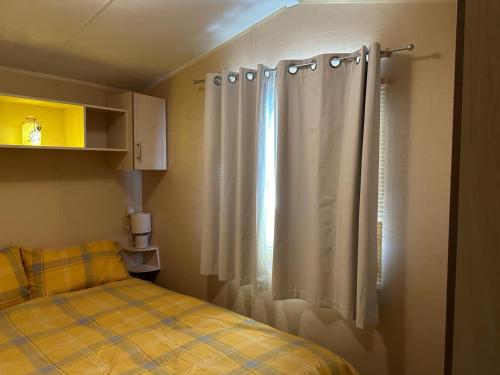 a bedroom with a bed and a window with a curtain at CaSa VistA - Holiday Home On The Beach in Clacton-on-Sea