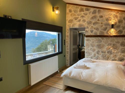 a bedroom with a bed and a large window at ToVouno in Plaka
