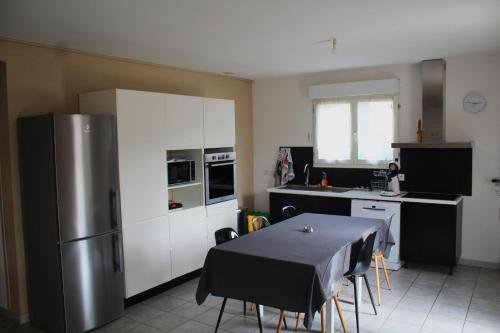 une cuisine avec une table et un réfrigérateur en acier inoxydable dans l'établissement Maison avec jacuzzi et vue sur les penitents, à Les Mées