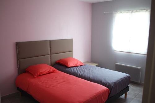 2 Betten mit roten Kissen im Schlafzimmer in der Unterkunft Maison avec jacuzzi et vue sur les penitents in Les Mées