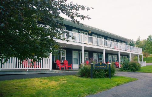 a building with red chairs in front of it at Ceilidh Country Lodge in Baddeck