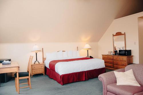 a hotel room with a large bed and a chair at Ceilidh Country Lodge in Baddeck