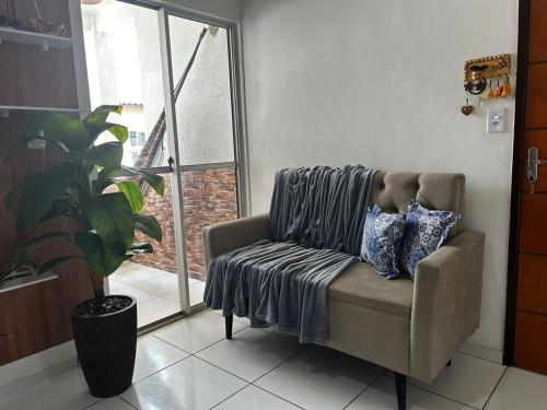 a couch with a blanket on it in a room with a window at Apto bem localizado est de Ribamar ao lado do shopping in São-José-do-Ribamar