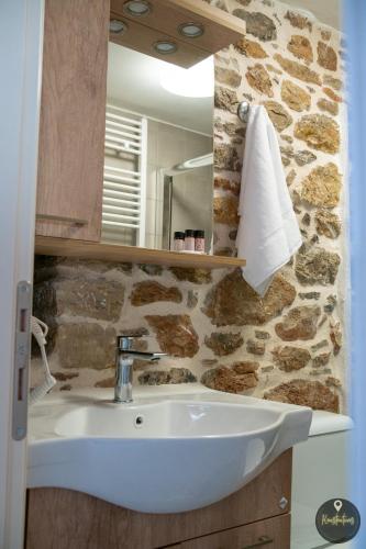 a bathroom with a sink and a stone wall at SKINOS rooms and apartment in Pyrgi
